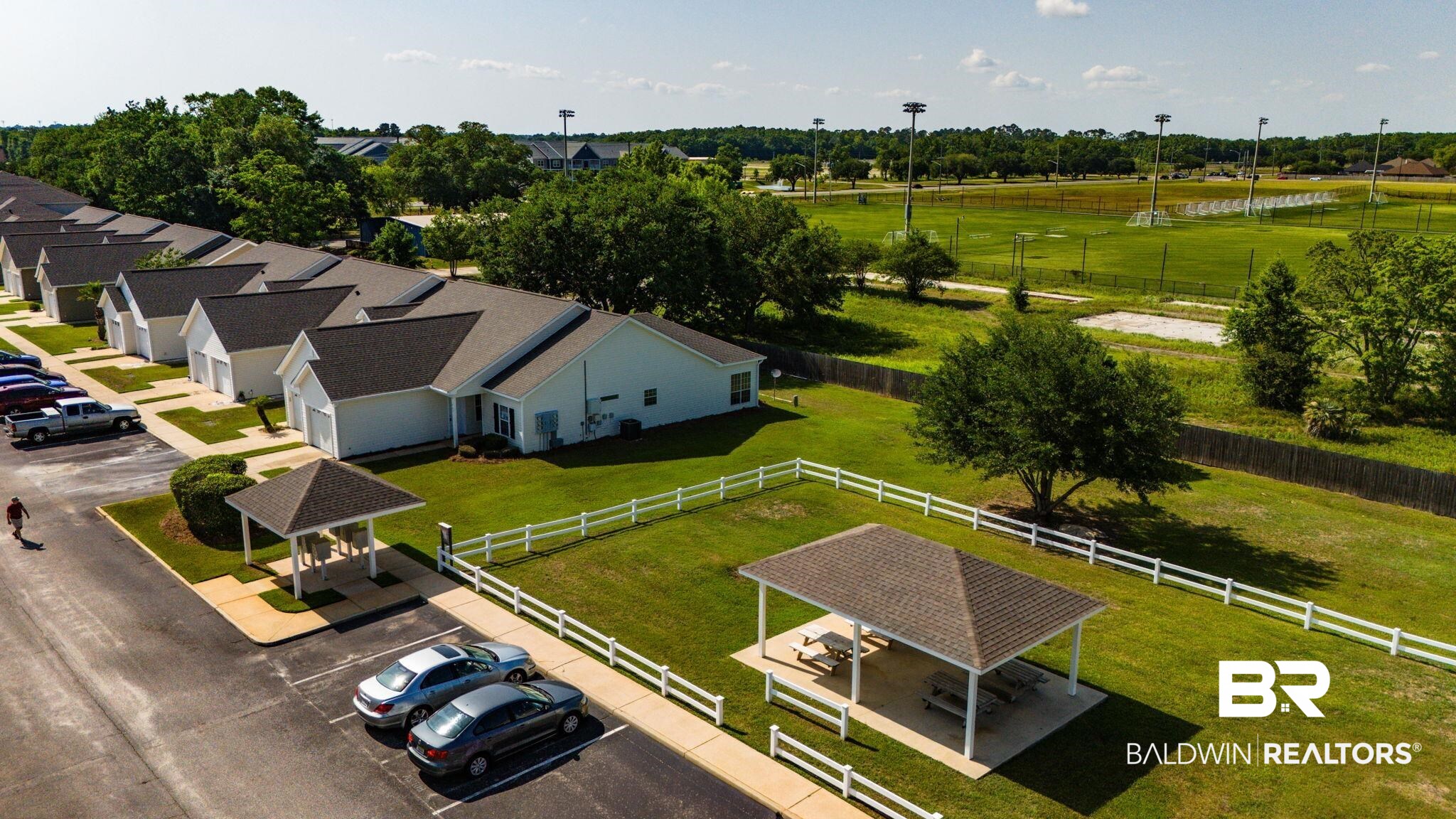 2651 South Juniper Street, Unit 705 Foley, AL 36535 - Photo 27 of 37 Community green space featuring a white picket fence, mature trees, and a covered picnic area with multiple tables