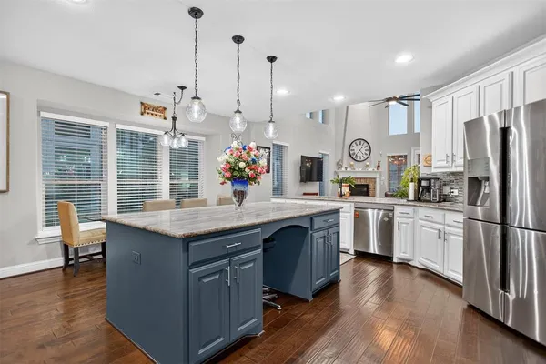 a kitchen with stainless steel appliances granite countertop a sink a stove a refrigerator and island with wooden floor