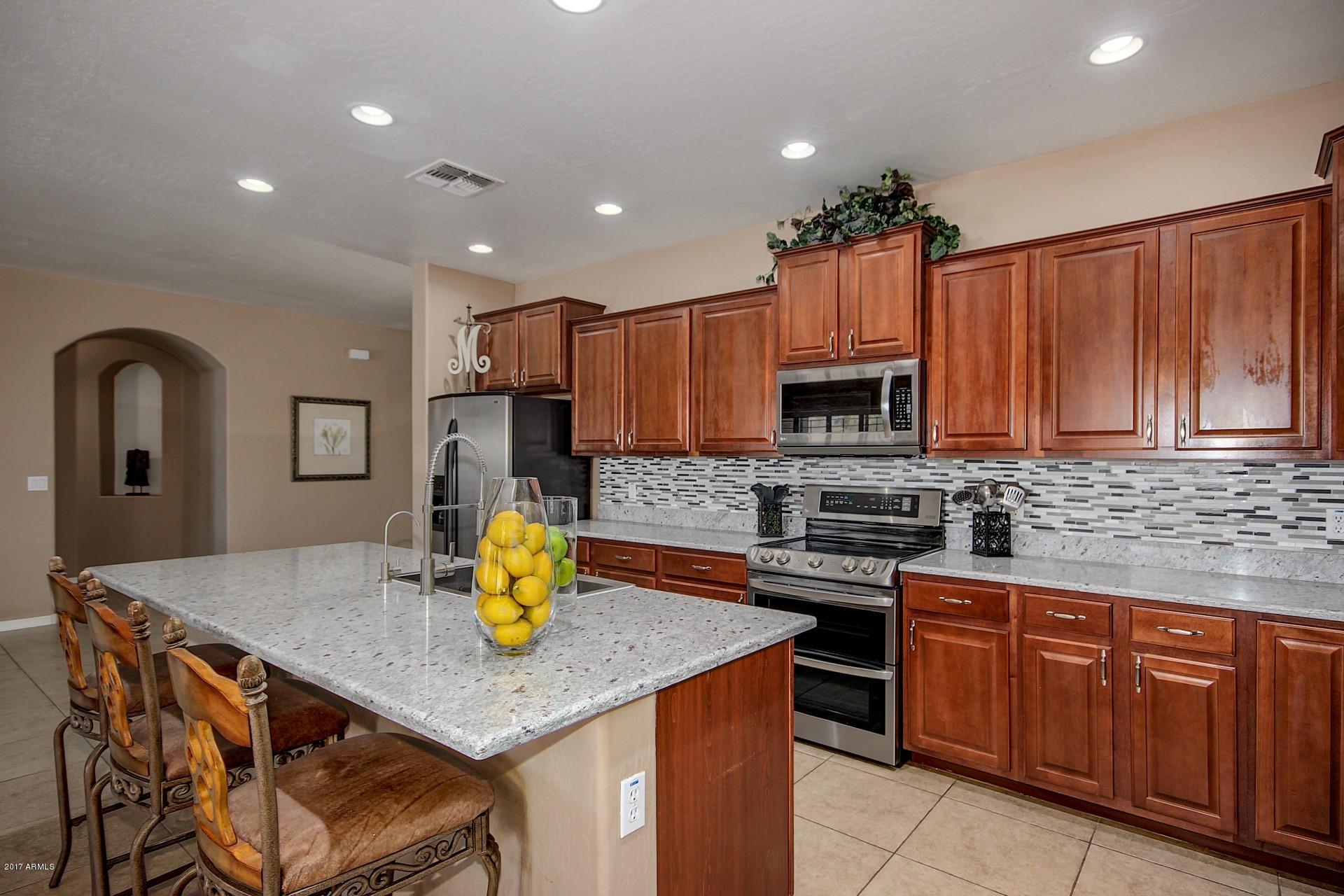 21982 East Rosa Road Queen Creek, AZ 85142 - Photo 18 of 40 a kitchen with granite countertop stainless steel appliances a stove refrigerator a sink a dining table and chairs