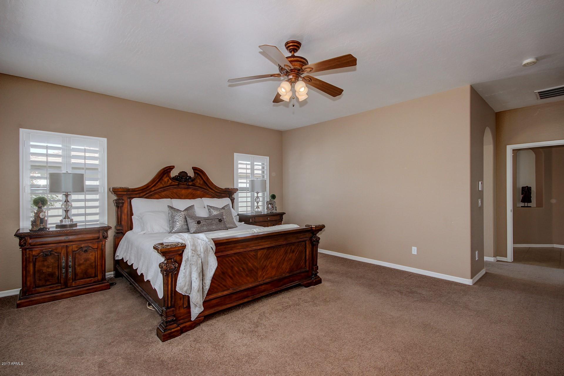 21982 East Rosa Road Queen Creek, AZ 85142 - Photo 27 of 40 a bedroom with a bed and a chandelier