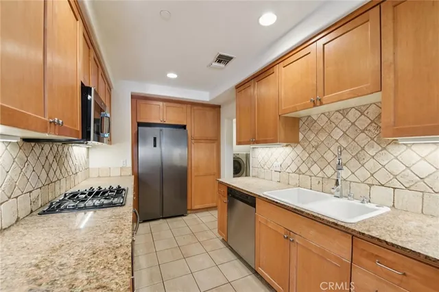 a kitchen with stainless steel appliances granite countertop a sink a stove and a refrigerator