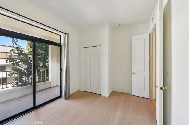 a view of an empty room with wooden floor and windows