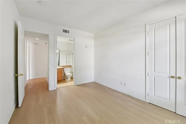 a view of an empty room with wooden floor and closet area