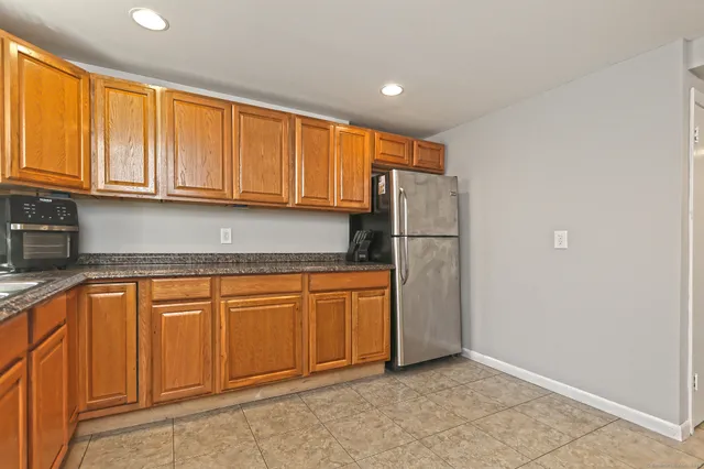 a kitchen with stainless steel appliances granite countertop a refrigerator a stove and a sink