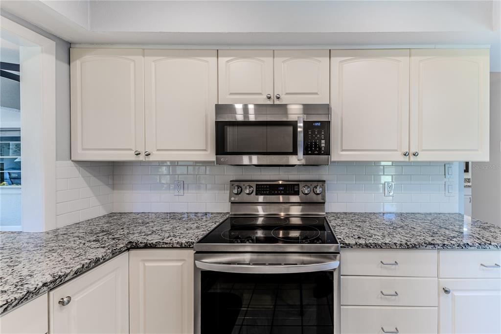 6428 Plantation Road Spring Hill, FL 34606 - Photo 23 of 50 a kitchen with stainless steel appliances granite countertop white cabinets and a stove a oven with white countertops