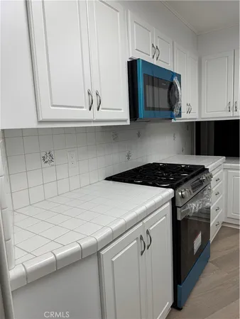 a kitchen with granite countertop white cabinets and a stove top oven
