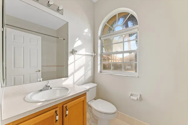 a bathroom with a granite countertop toilet a sink and a mirror