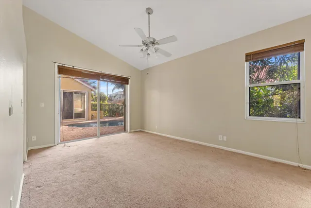 an empty room with windows and chandelier fan