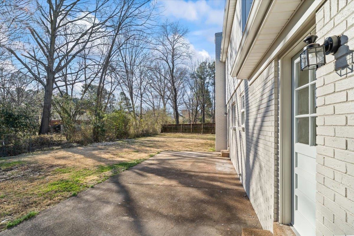 1676 Miller Farms Road Germantown, TN 38138 - Photo 28 of 37 Property exterior featuring light-colored brick siding, a white paneled door with window inserts, and an exterior wall lantern