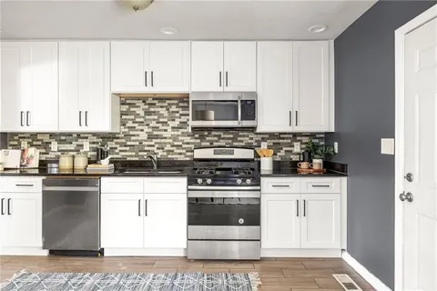 a kitchen with stainless steel appliances granite countertop a stove a sink and white cabinets