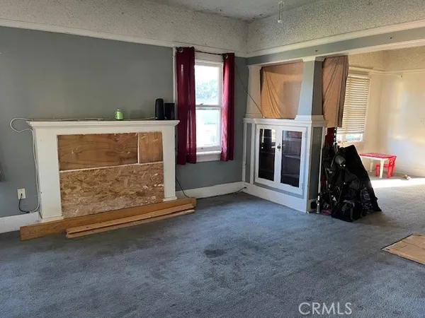 a view of an empty room with fireplace and windows