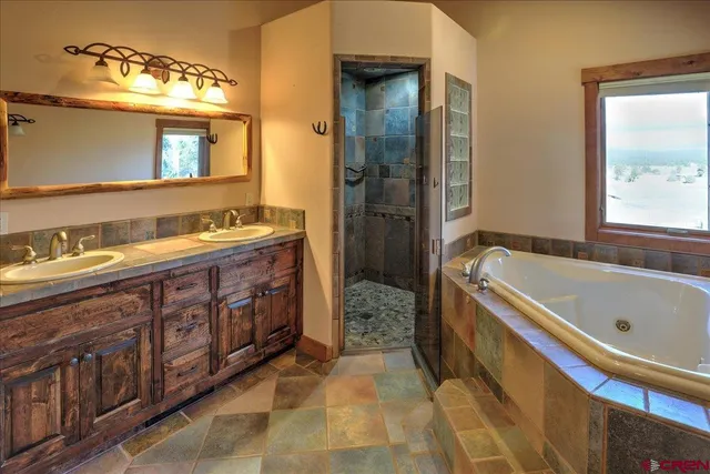 a spacious bathroom with a tub sink and mirror