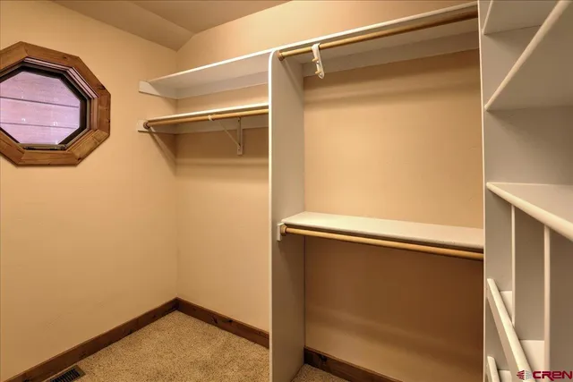 a view of walk in closet with clothes and window