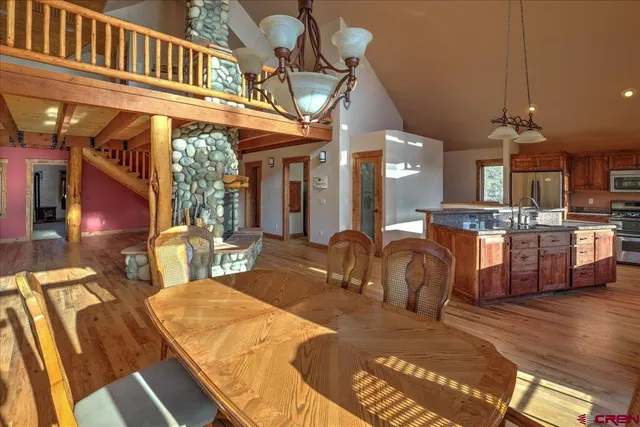 a view of a dining room and livingroom with furniture a chandelier and wooden floor