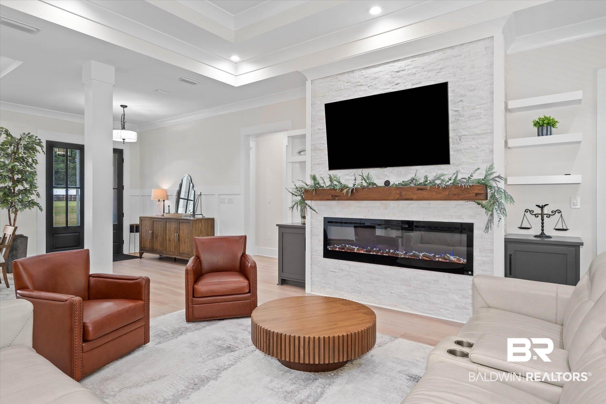 11 Creax Road Axis, AL 36505 - Photo 4 of 46 Spacious living area featuring a stacked stone fireplace with an integrated electric insert, a wood mantel, and built-in floating shelves