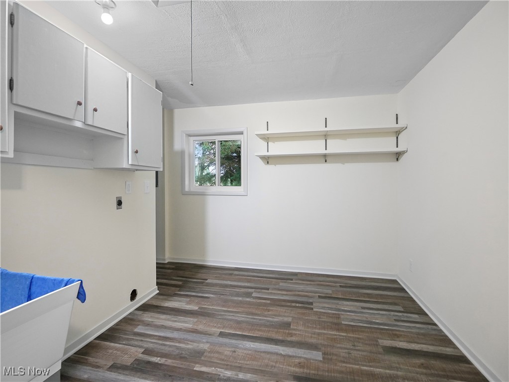 6875 Morrell Ray Road Bristolville, OH 44402 - Photo 27 of 39 Laundry room featuring baseboards, dark wood-style floors, cabinet space, hookup for an electric dryer, and a textured ceiling