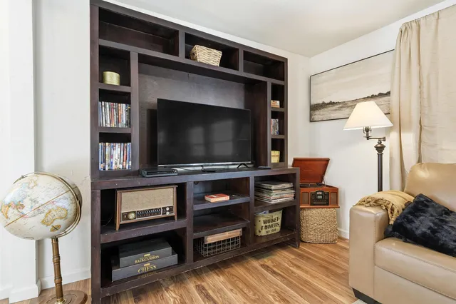 a kitchen with stainless steel appliances granite countertop a stove top oven a refrigerator a sink and white cabinets with wooden floor