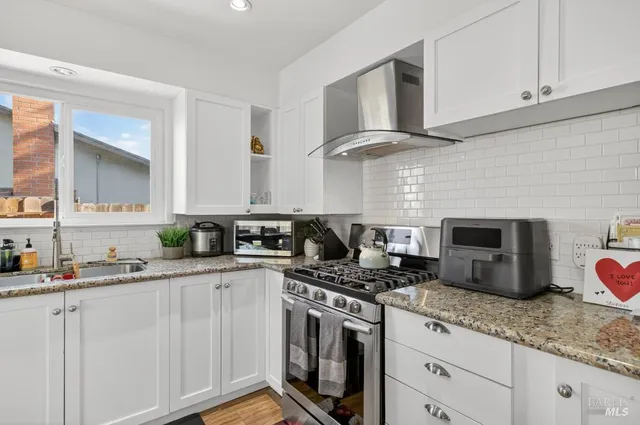 a kitchen with granite countertop a counter space dining table stainless steel appliances and wooden floor
