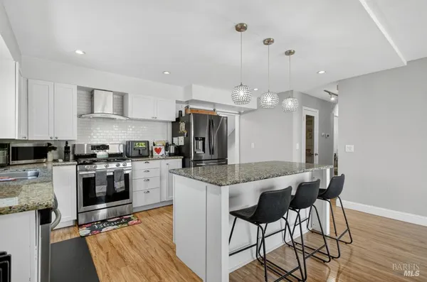 a kitchen with a table chairs refrigerator and wooden floor