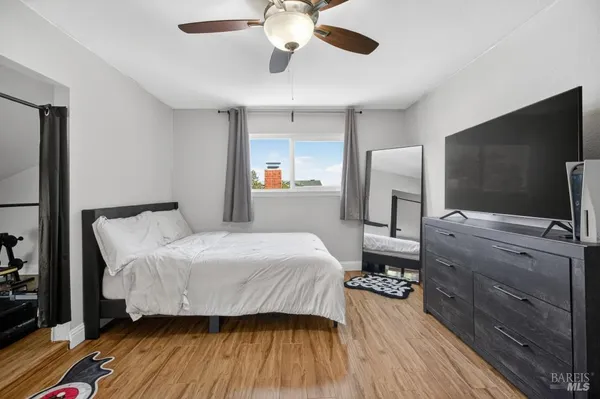 a view of a hallway with wooden floor and a bathroom