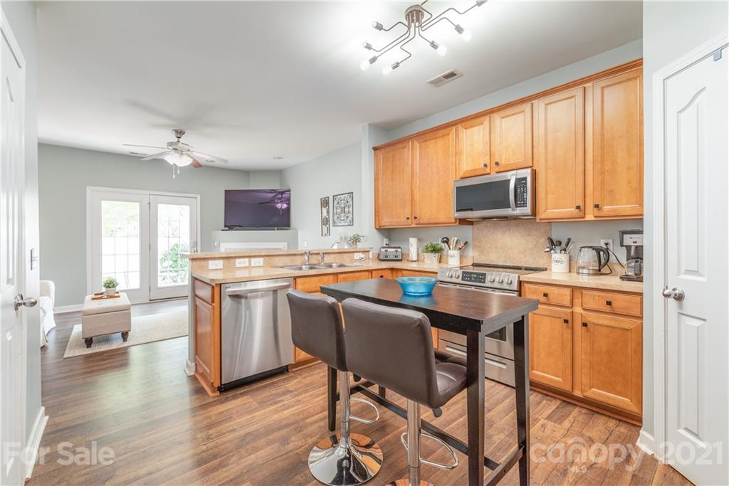 1131 Market Street Fort Mill, SC 29708 - Photo 7 of 27 a kitchen with stainless steel appliances granite countertop a stove top oven a sink dishwasher a dining table and chairs with wooden floor