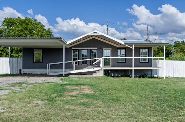 a view of a house with a yard and a large tree
