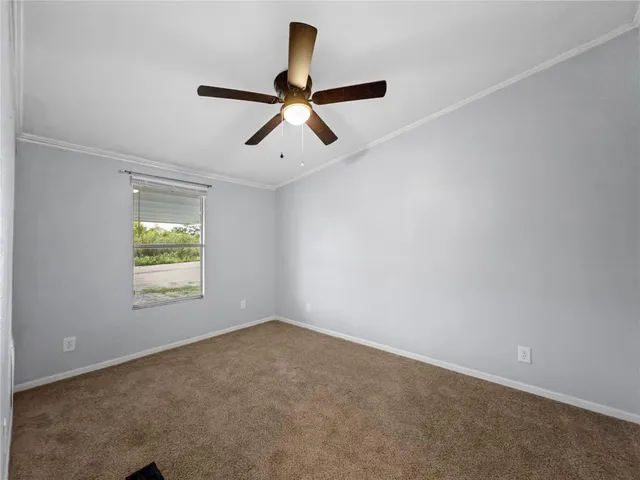 an empty room with ceiling fan and windows