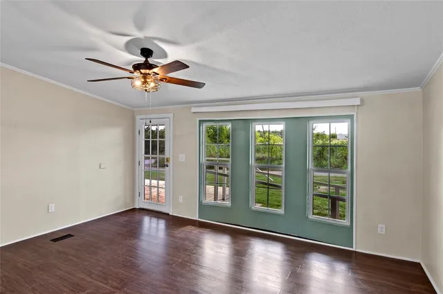 a view of an empty room with a window and wooden floor