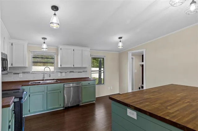 a kitchen with kitchen island a sink dishwasher a stove and white countertops with wooden floor