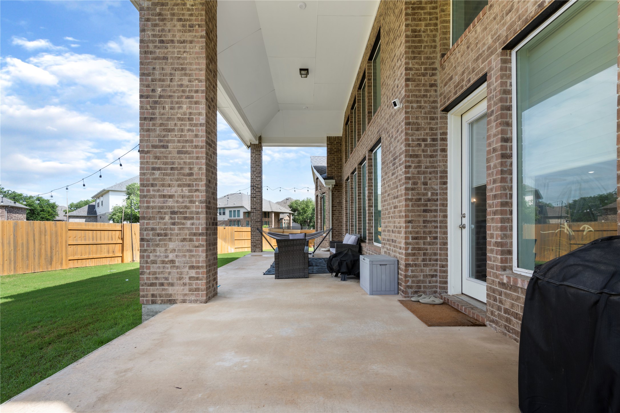 105 Autumn Oak Way Georgetown, TX 78628 - Photo 37 of 40 Expansive covered patio featuring brick columns, a concrete surface, and direct access to a grassy yard enclosed by a wooden privacy fence