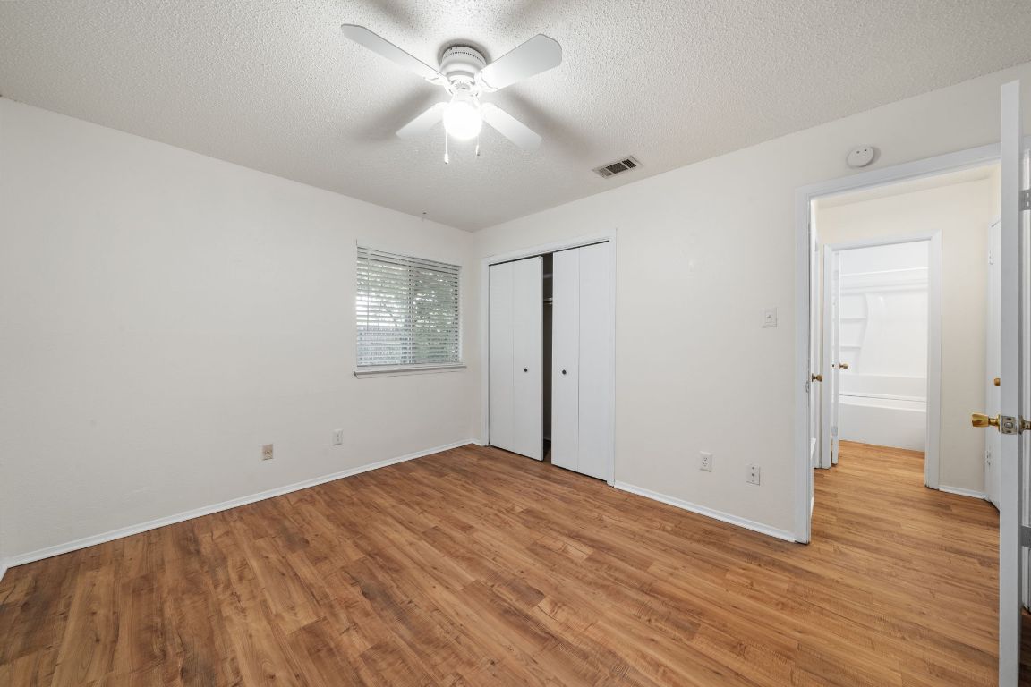 100 Meteor Drive, Unit B Austin, TX 78745 - Photo 16 of 29 Unfurnished bedroom featuring light wood finished floors, a textured ceiling, a closet, and a ceiling fan