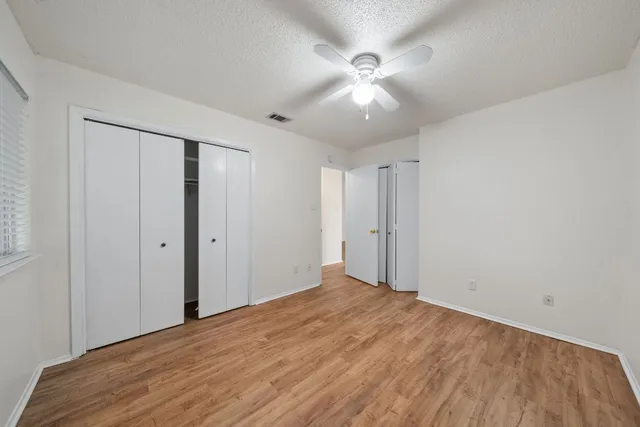 an empty room with wooden floor and ceiling fan