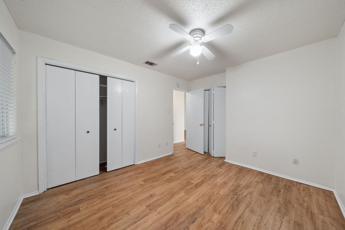 100 Meteor Drive, Unit B Austin, TX 78745 - Photo 17 of 29 Unfurnished bedroom with light wood-style flooring, a textured ceiling, a closet, and a ceiling fan