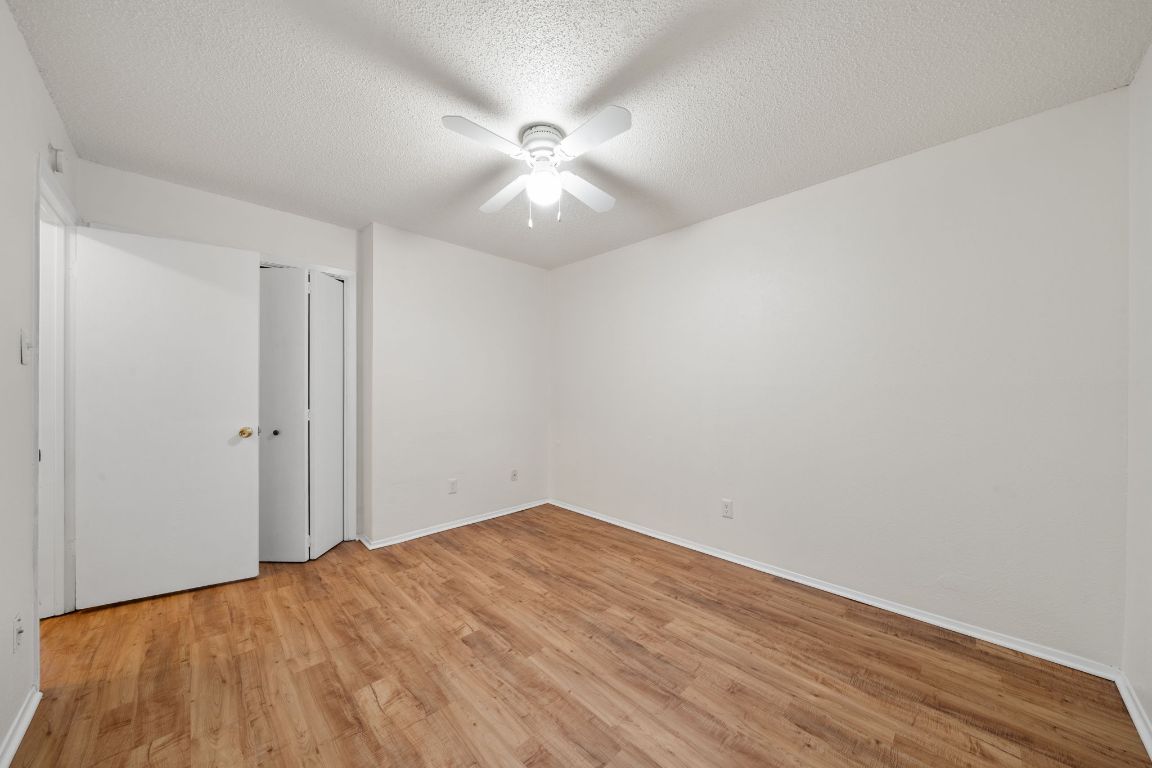 100 Meteor Drive, Unit B Austin, TX 78745 - Photo 18 of 29 Unfurnished bedroom with light wood finished floors, a textured ceiling, ceiling fan, and a closet