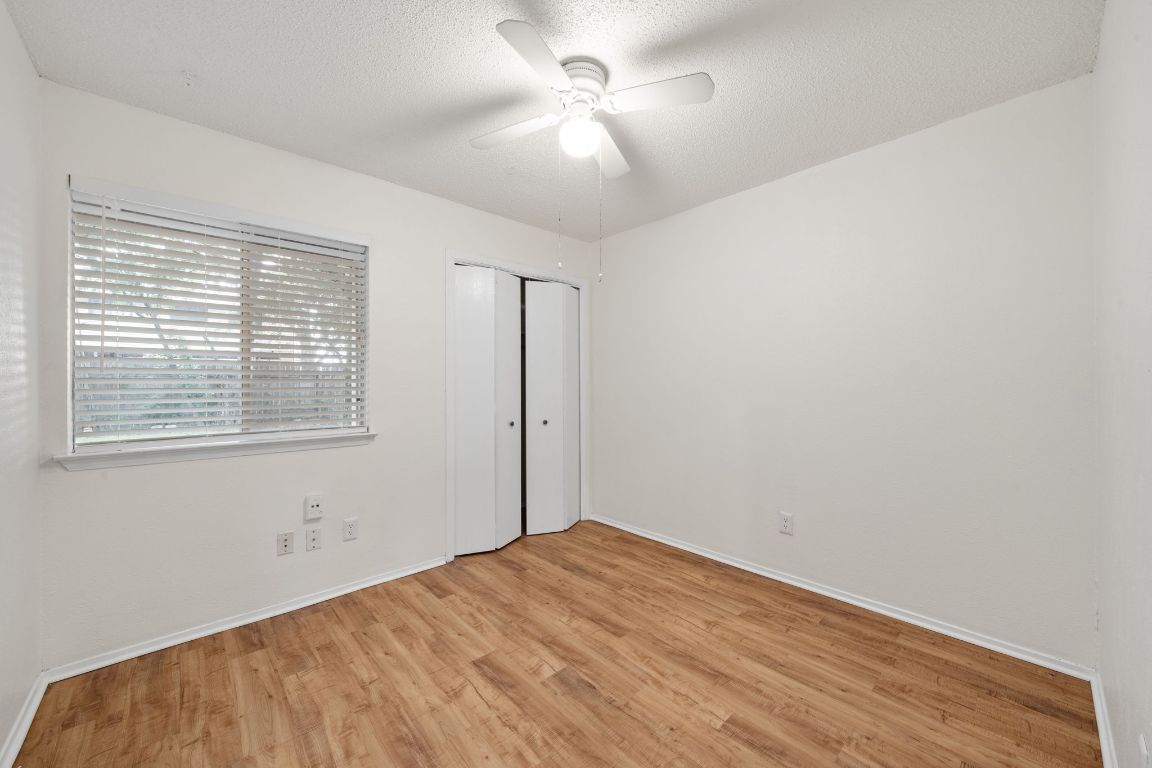 100 Meteor Drive, Unit B Austin, TX 78745 - Photo 19 of 29 Unfurnished bedroom featuring light wood finished floors, a textured ceiling, a ceiling fan, and a closet