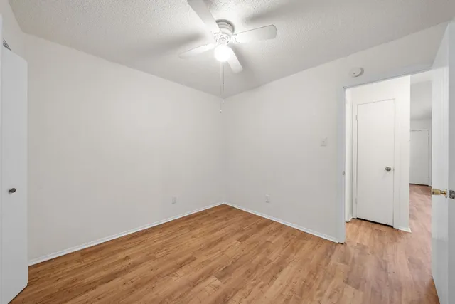 a view of empty room with wooden floor and fan