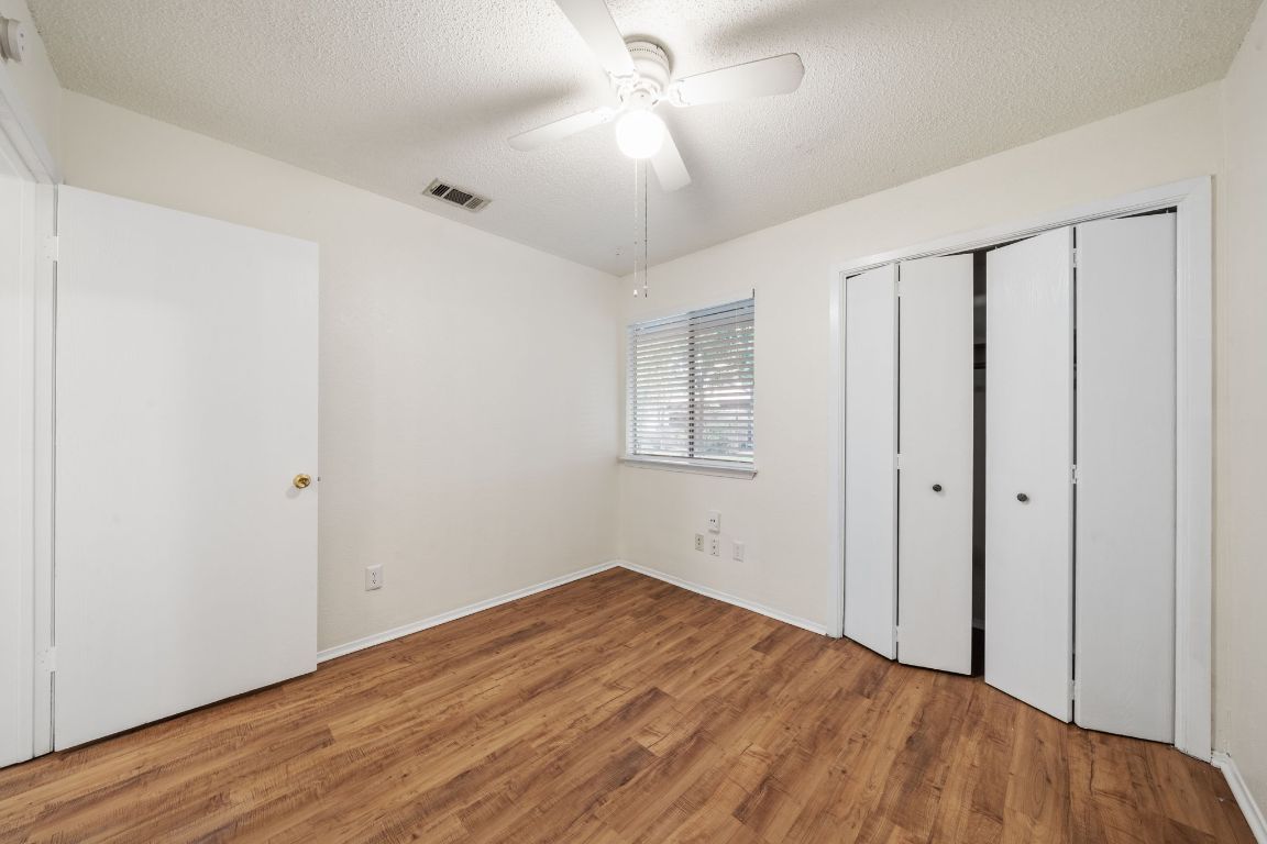 100 Meteor Drive, Unit B Austin, TX 78745 - Photo 22 of 29 Unfurnished bedroom featuring wood finished floors, a textured ceiling, ceiling fan, and a closet