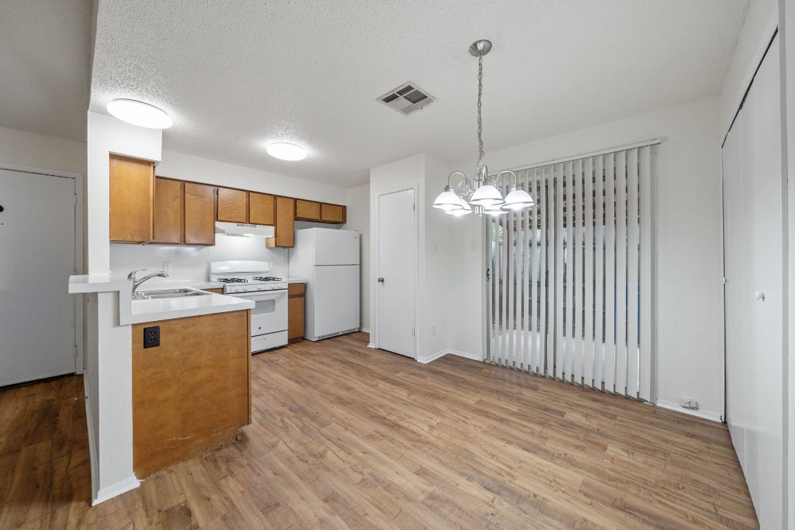 100 Meteor Drive, Unit B Austin, TX 78745 - Photo 6 of 29 Kitchen with brown cabinets, light countertops, white appliances, pendant lighting, and light wood-type flooring