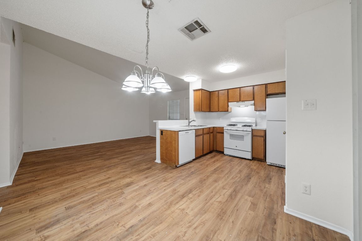 100 Meteor Drive, Unit B Austin, TX 78745 - Photo 29 of 29 Kitchen featuring light countertops, a chandelier, open floor plan, white appliances, and brown cabinetry