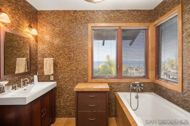 a bathroom with a tub sink and mirror