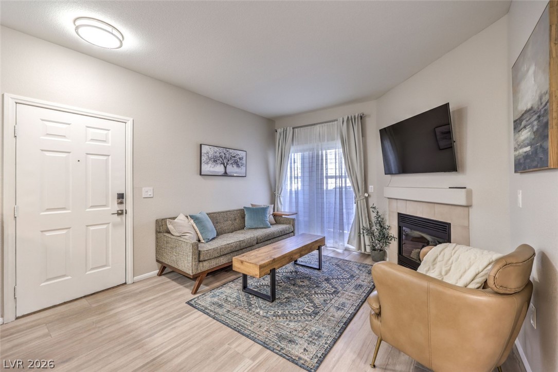 855 North Stephanie Street, Unit 1015 Henderson, NV 89014 - Photo 2 of 27 Living room with a tiled fireplace and light wood-type flooring