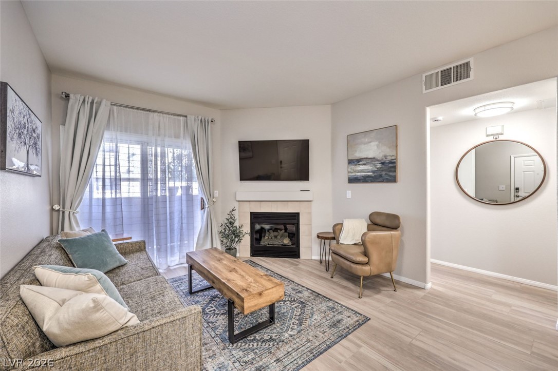 855 North Stephanie Street, Unit 1015 Henderson, NV 89014 - Photo 3 of 27 Living room with a tiled fireplace and light wood-type flooring