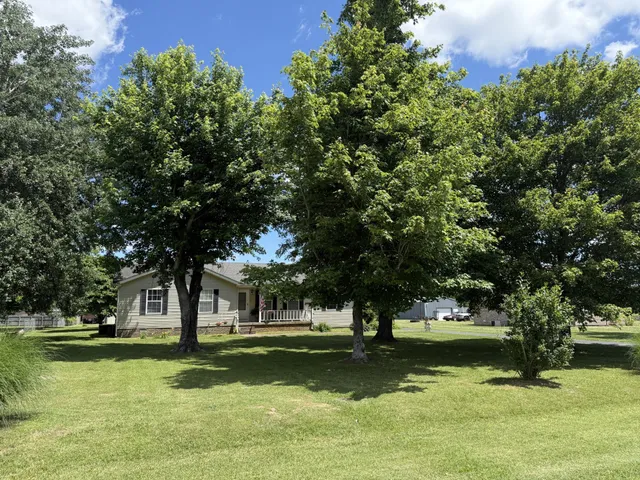 a view of a fountain in front of a house with large trees