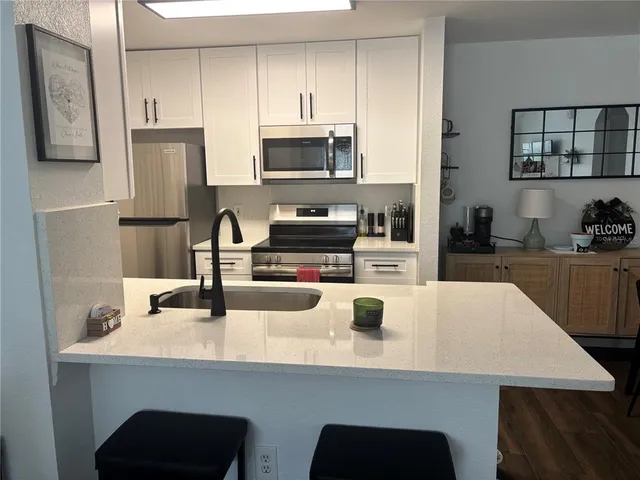 a kitchen with stainless steel appliances a microwave a stove a sink a refrigerator and wooden cabinets