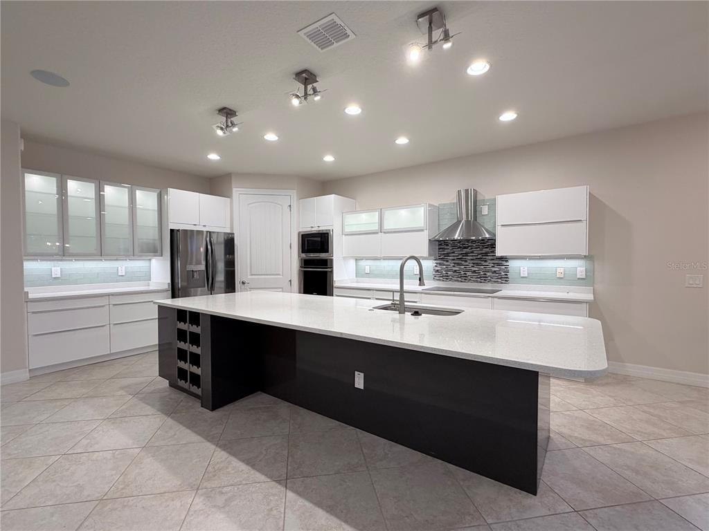 10041 Southwest 77th Loop Ocala, FL 34481 - Photo 3 of 39 a large kitchen with kitchen island a sink stainless steel appliances and cabinets