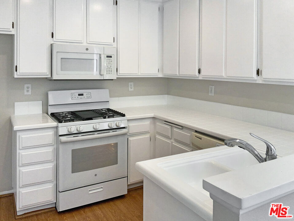 11074 Kenyon Way Rancho Cucamonga, CA 91701 - Photo 11 of 28 a kitchen with white cabinets and white appliances