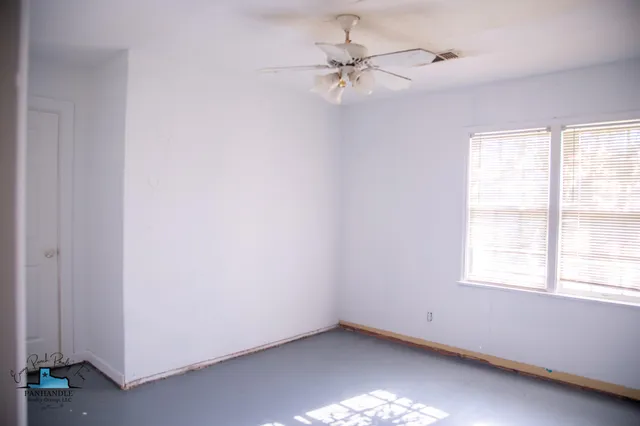 an empty room with a window and a fan