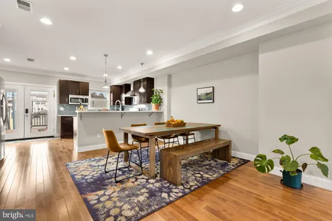 a kitchen with stainless steel appliances granite countertop a stove top oven a dining table and chairs with wooden floor