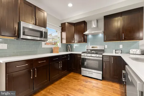a kitchen with stainless steel appliances granite countertop a stove a sink and a microwave