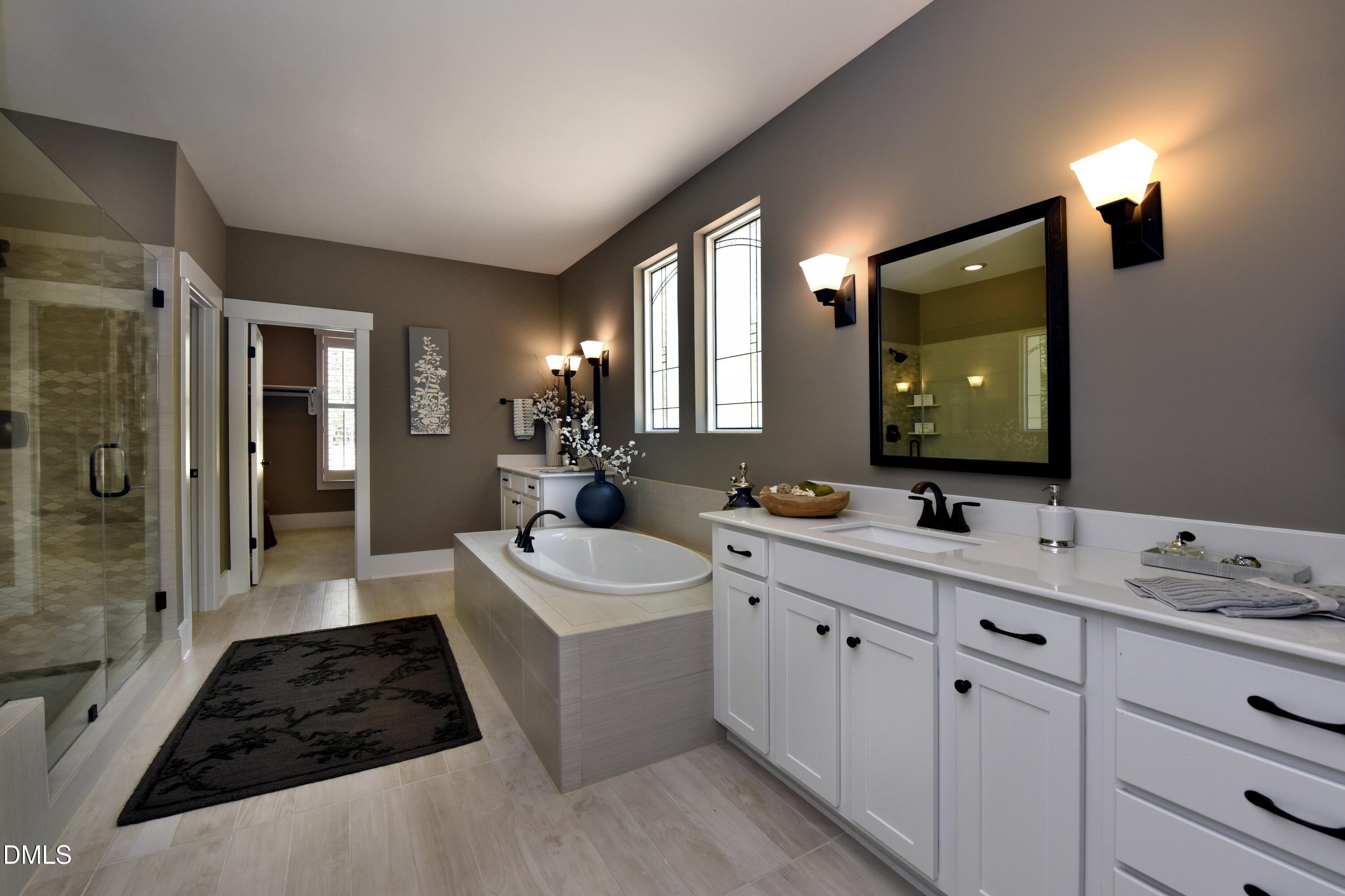 4 Wolf Tree Way Efland, NC 27243 - Photo 13 of 28 a bathroom with a double vanity sink a large mirror a bathtub and shower